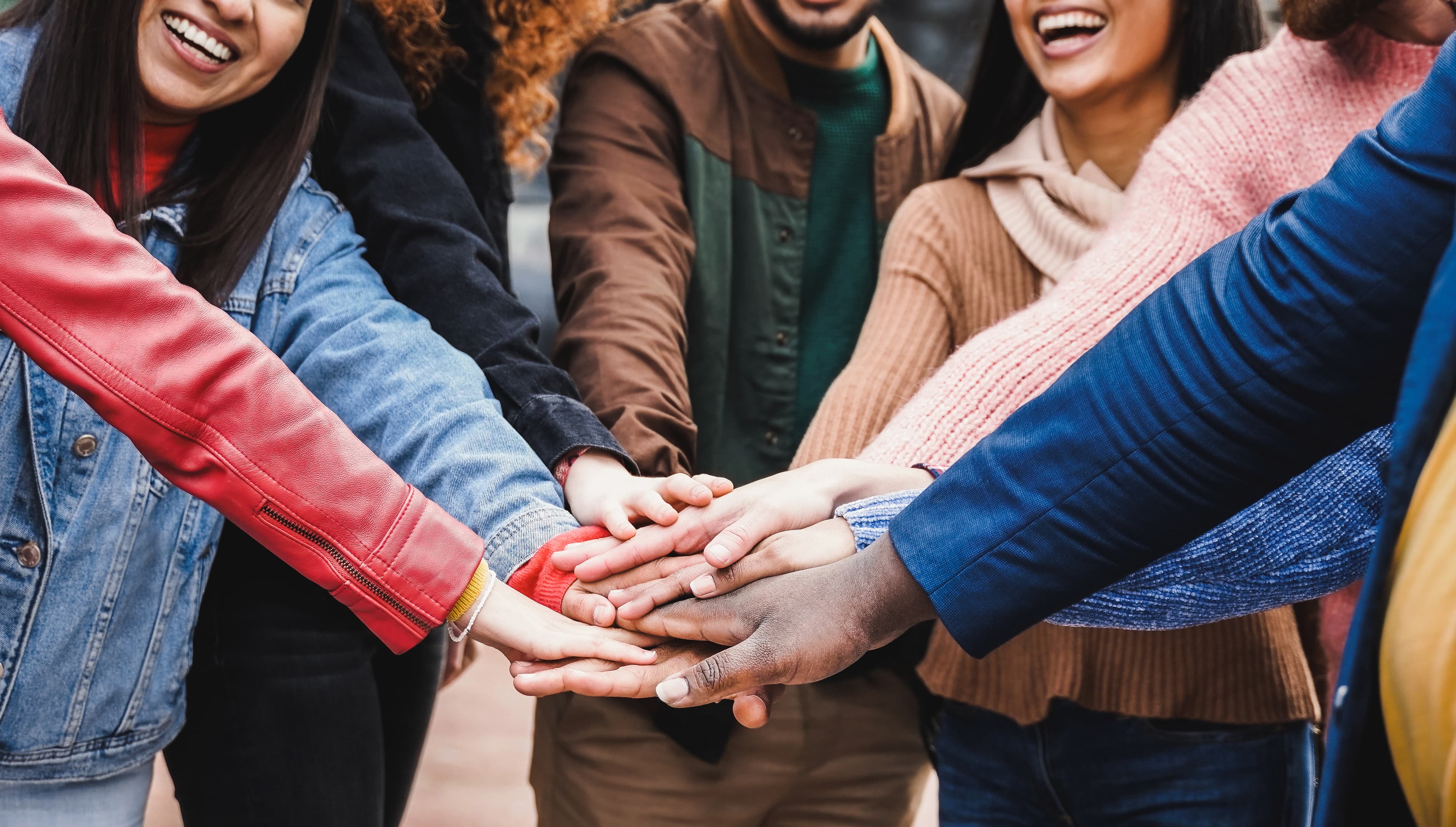 A circle of hands stacked together — community and shared commitment